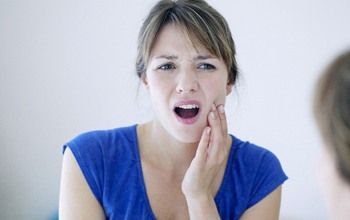 Woman in blue shirt with jaw pain